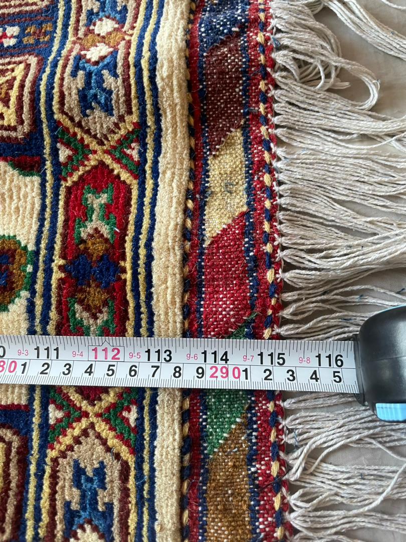 Close-up of a patterned rug with a measuring tape for scale