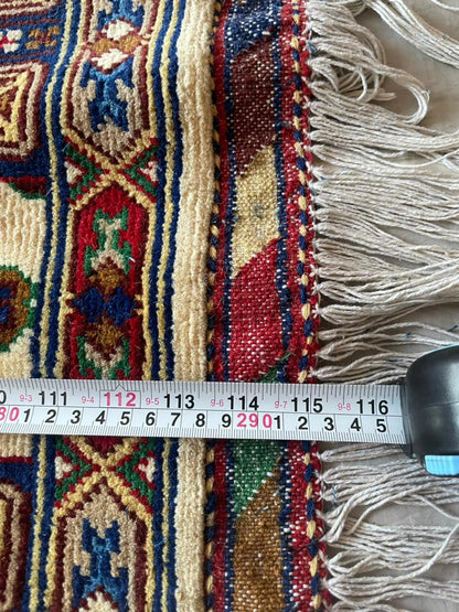 Close-up of a patterned rug with a measuring tape for scale